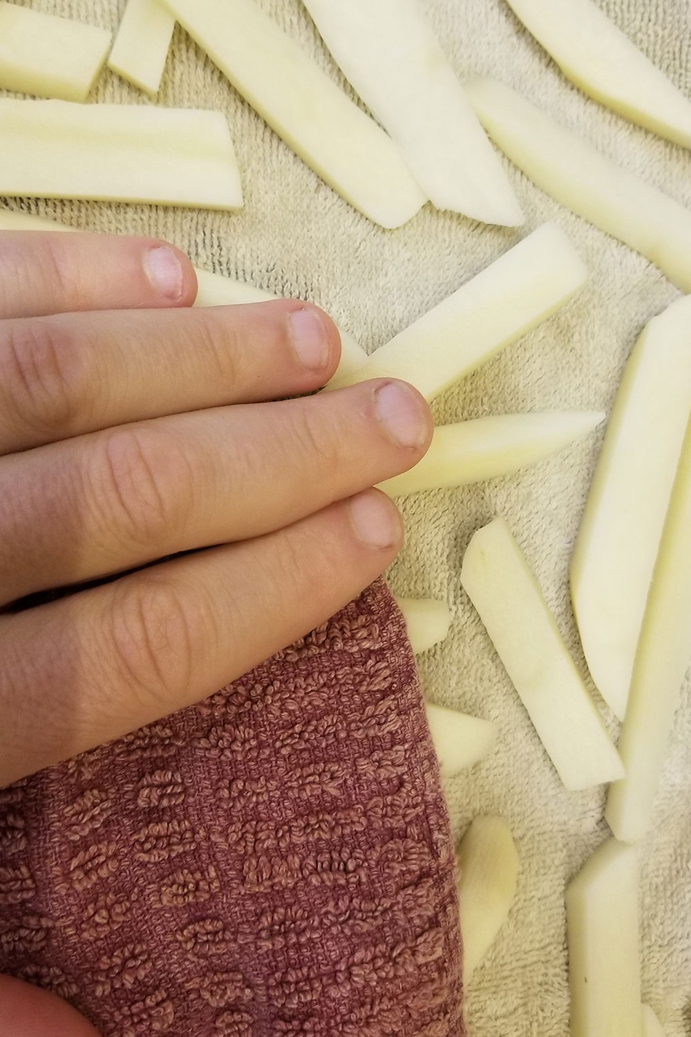 Patting potatoes dry with a clean dishcloth