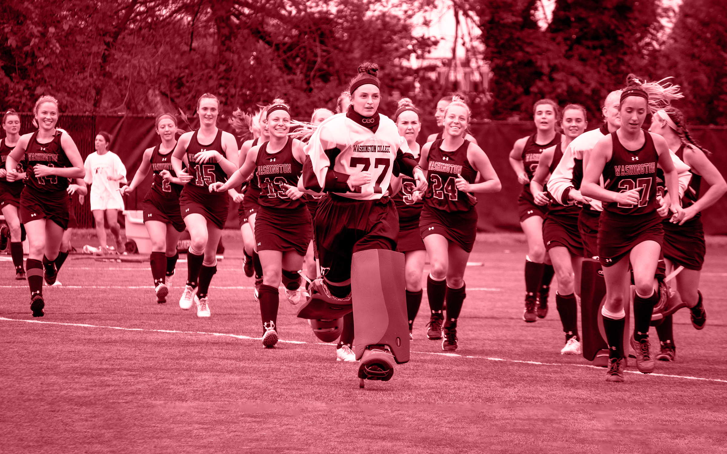 Washington College women's field hockey players running and smiling