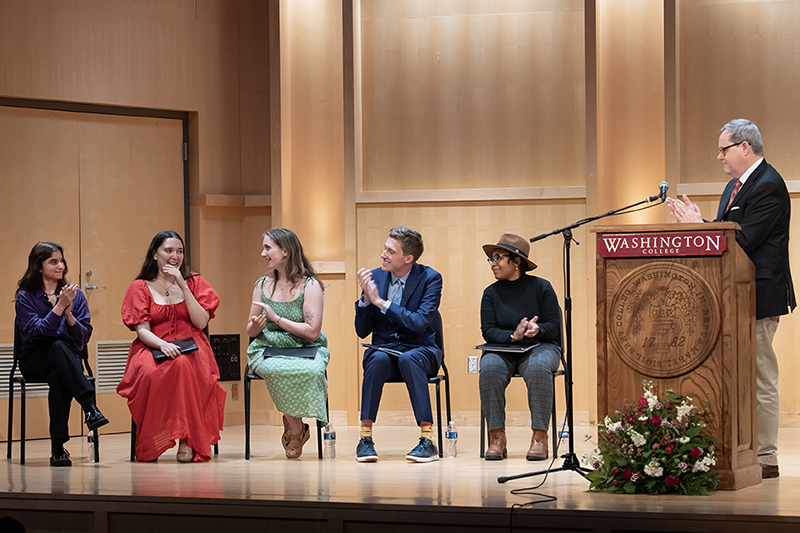 Eylie Sasajima reacts after being named the winner of the 2023 Sophie Kerr Prize as the other finalists and President Mike Sosulski applaud.