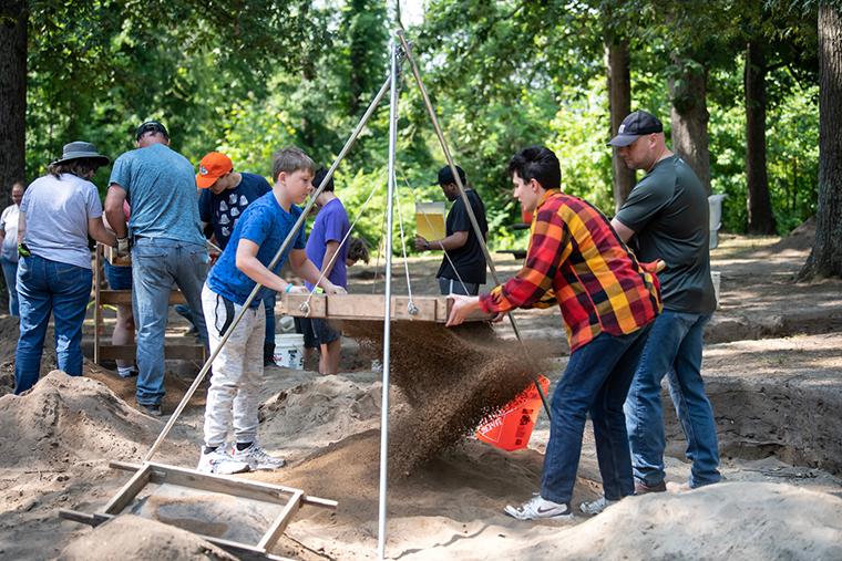 Public volunteers sift earth dug from the archaeological site.