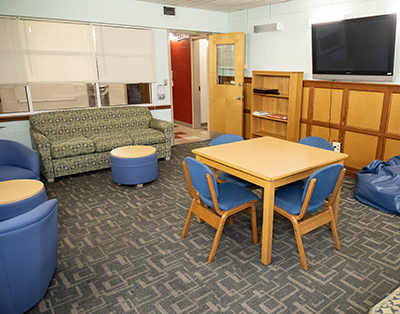 a lounge with table, chairs, TV, and couch