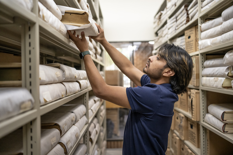 Washington College student Felipe Tassara pulls record books from the shelves of the Maryland State Archives