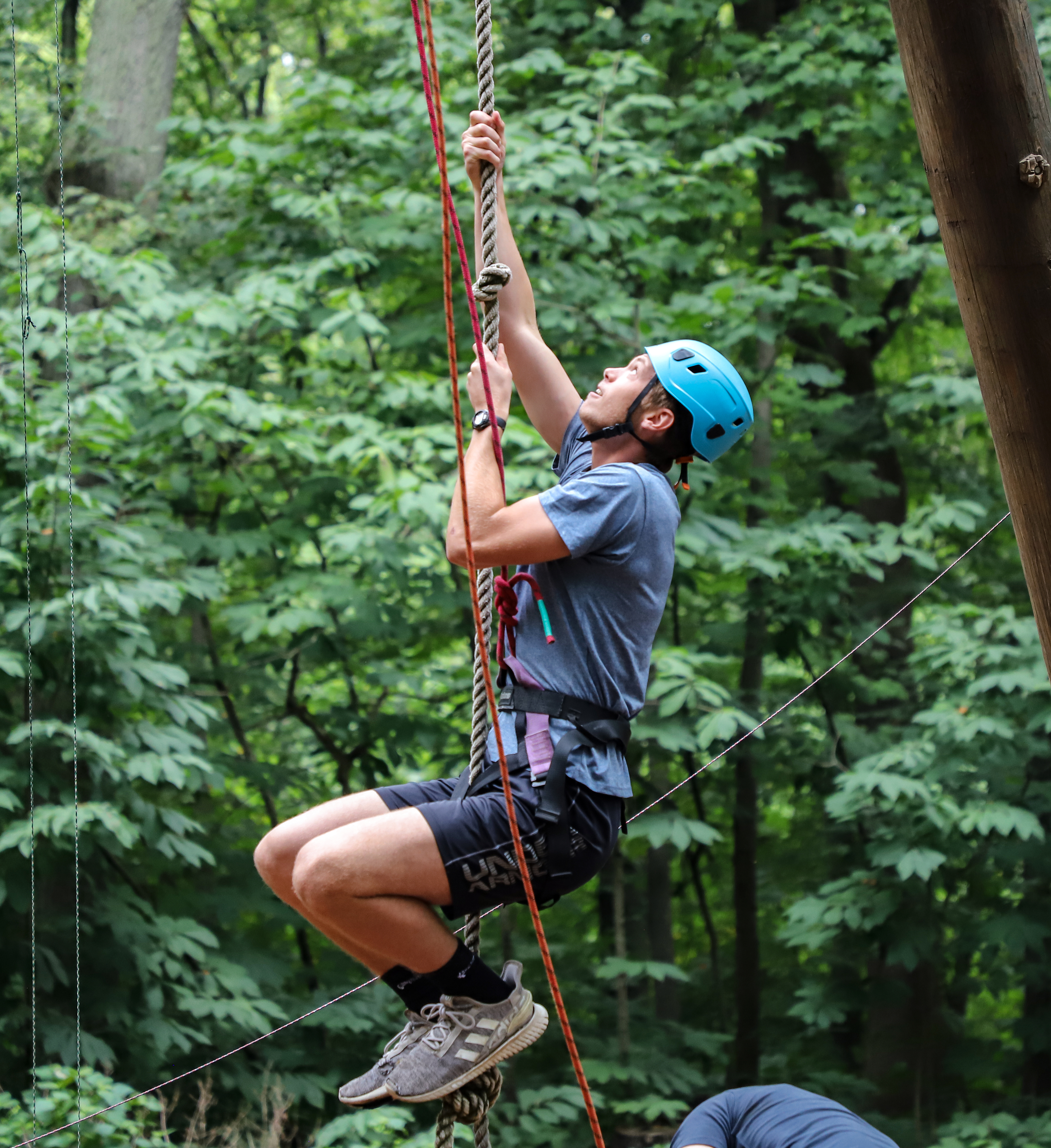 student riding a zipline through the trees