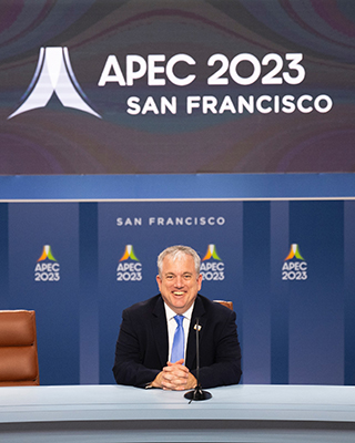 Matt Murray '95 sitting at a table under a sign saying APEC 2023 San Francisco