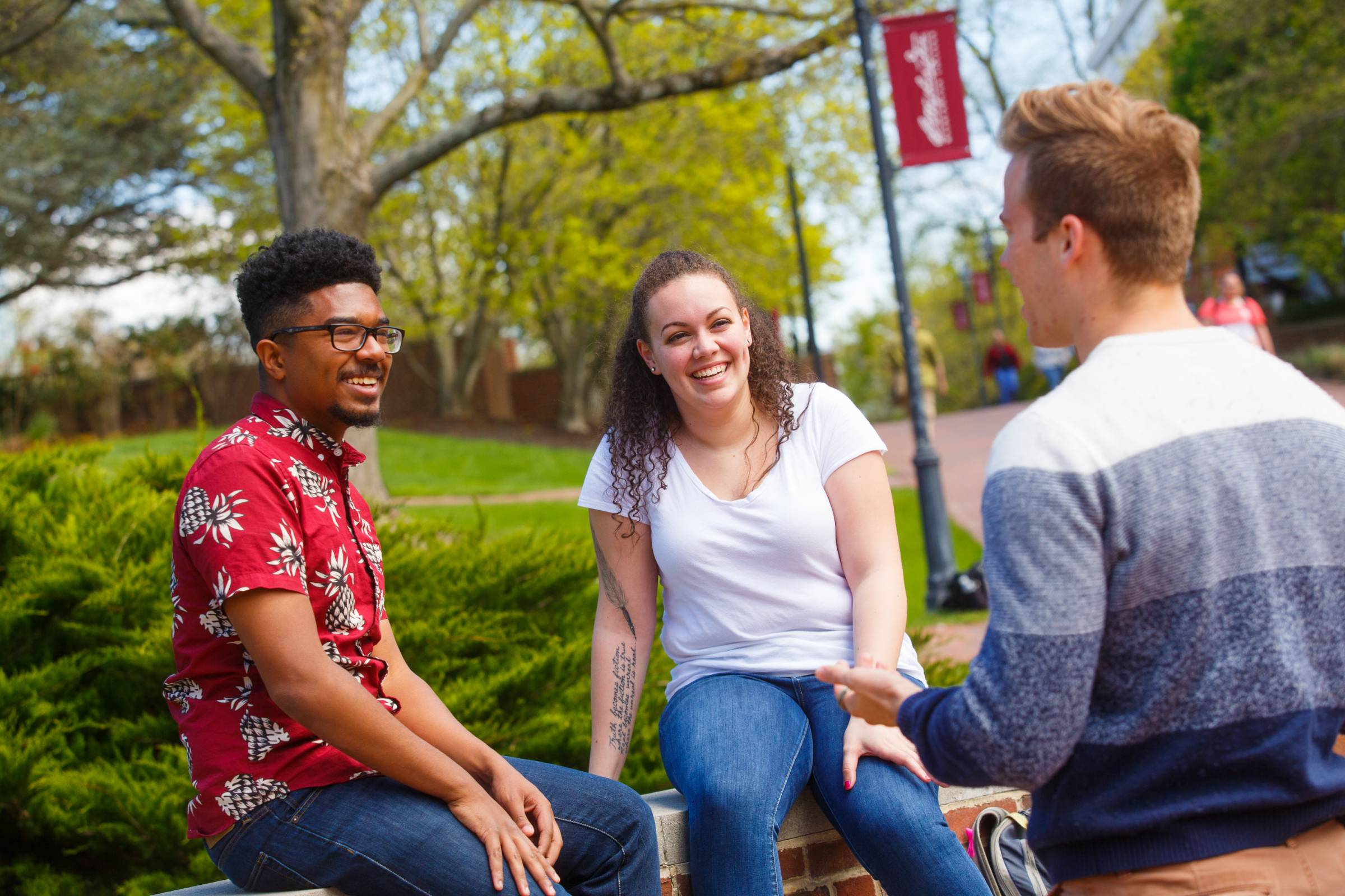 three students sitting on a bench outside