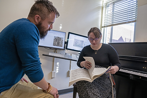 a student and faculty member look at a bound musical score