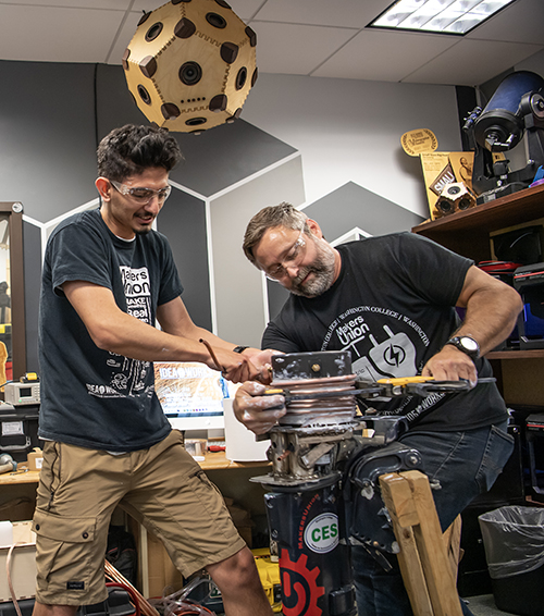 A student and staff member work on an electric motor in the makerspace