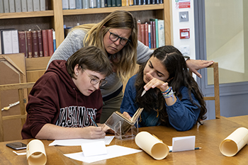 students and a faculty member examine an old book