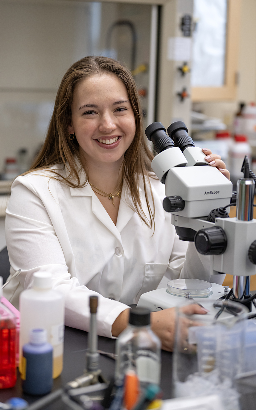 Emily Kopp sits at a microscope